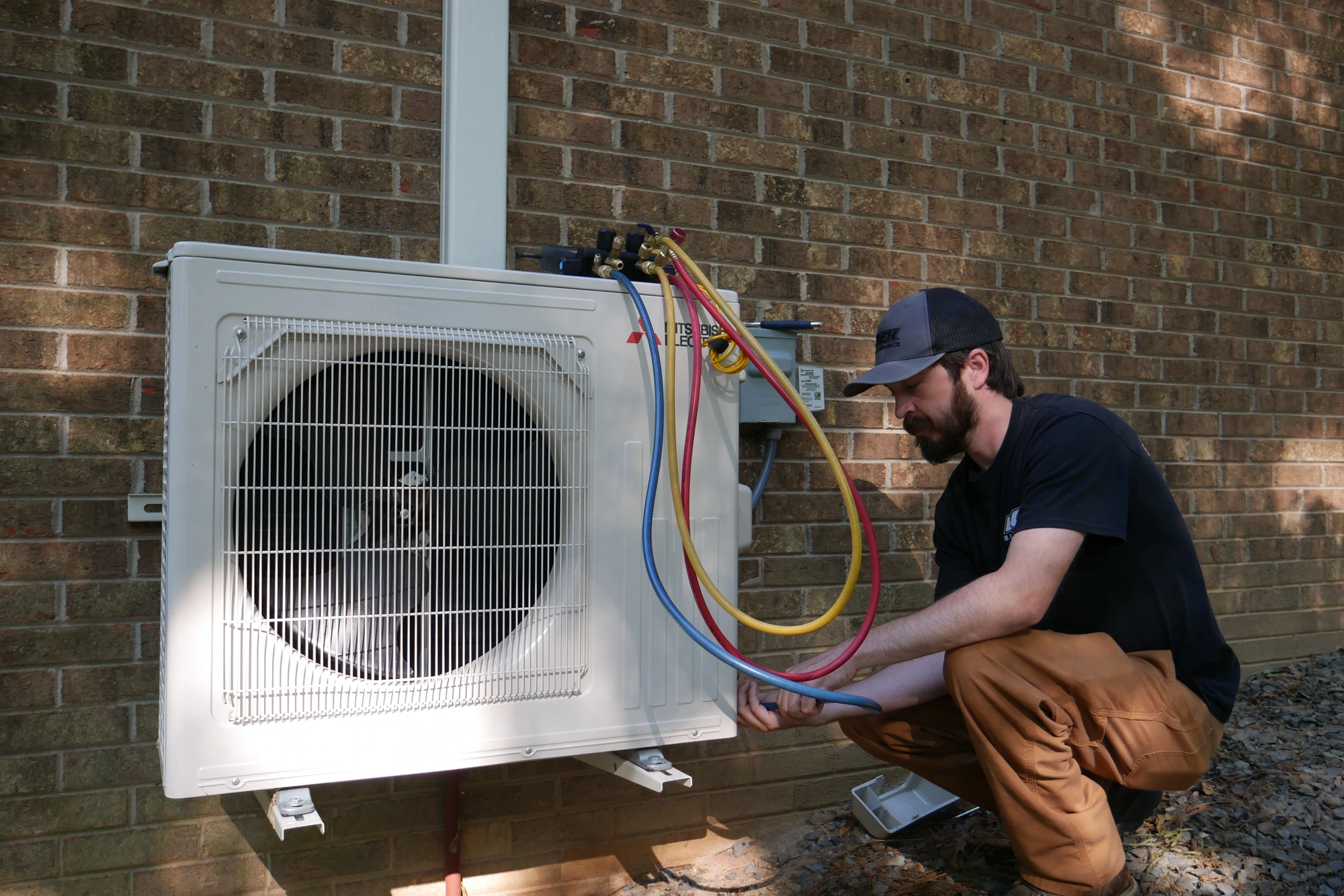 B.E. Holbrooks Co. technician checking refrigerant gauges on a residential heat pump in Stanfield, NC